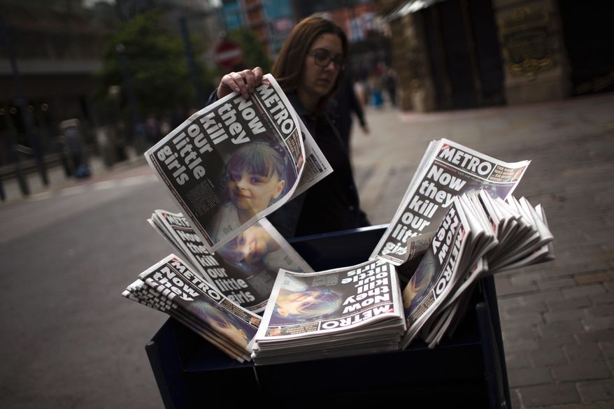 A woman picks a newspaper reporting the news on the suicide attack at a concert by Ariana Grande that killed more than 20 people as it ended Monday night in central Manchester, Britain, Wednesday, May 24, 2017. (AP Photo/Emilio Morenatti)