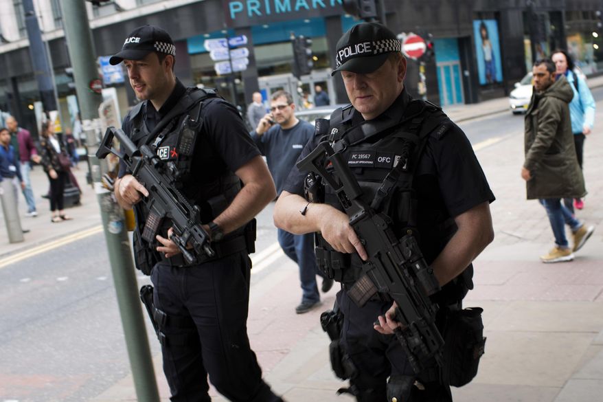 Police officers patrol in central Manchester, Britain, Wednesday, May 24, 2017 after Monday's suicide attack at an Ariana Grande concert. Britons will find armed troops at vital locations Wednesday after the official threat level was raised to its highest point. (AP Photo/Emilio Morenatti)