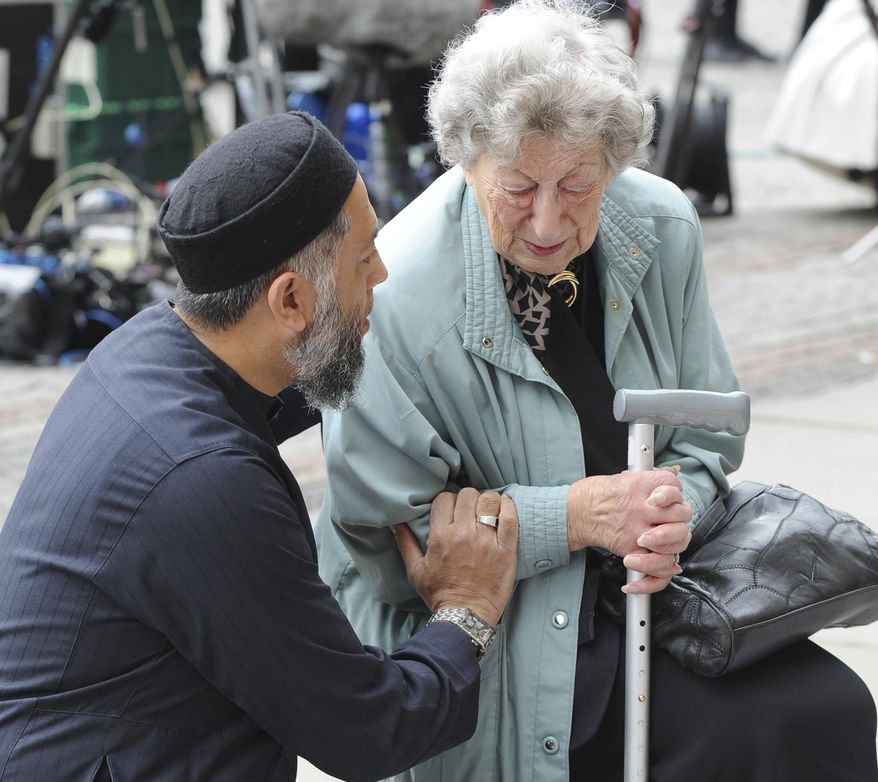 Renee Rachel Black, right, is comforted by Sadiq Patel in front of flower tributes at Albert Square central Manchester, England Wednesday May 24 2017. Police confirmed that more than 20 people were killed in an explosion following a Ariana Grande concert at the Manchester Arena late Monday evening. Britons will find armed troops at vital locations Wednesday after the official threat level was raised to its highest point. (AP Photo/Rui Vieira)