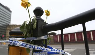 Flowers are attached to a railing close to Victoria Railway Station in Manchester, Britain, Wednesday, May 24, 2017, after Monday&#39;s suicide attack at an Ariana Grande concert. Britons will find armed troops at vital locations Wednesday after the official threat level was raised to its highest point. (AP Photo/Dave Thompson)