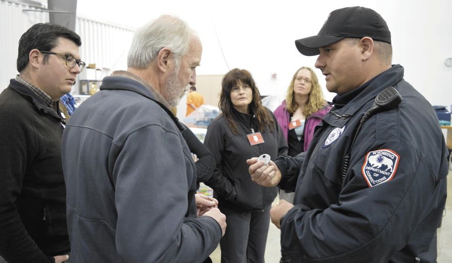 In this undated photo, Carbon County Higher Education Center director David Throgmorton speaks to Sgt. Wrisley of the Wyoming State Penitentiary, who helped show around a tour of the Pen's industries, a garment shop and print shop which help save the state money and rehabilitate inmates in Woessner, Wyo. The garment shop is enormous, with numerous stations and rows of tables bearing sewing machines and model clothing. (Iain Woessner/The Rawlins Daily Times via AP)