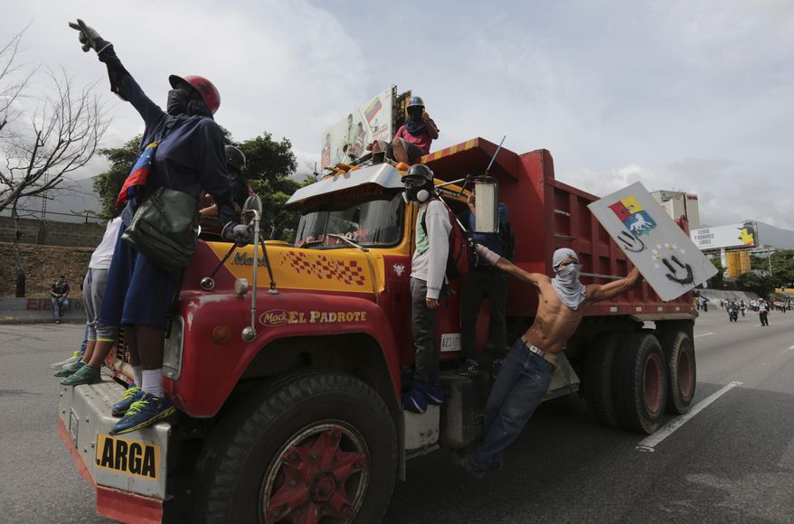 Anti-government protesters take over a cargo truck as they clash with security forces blocking their mach from reaching the National Electoral Council headquarters in Caracas, Venezuela, Wednesday, May 24, 2017. Demonstrators contend Venezuelan President Nicolas Maduro's government is quickly becoming a full-fledged authoritarian regime, and that his call to rewrite the constitution is one more attempt to consolidate his power. They are also decrying Venezuela's triple-digit inflation, soaring crime and vast food shortages. (AP Photo/Fernando Llano)