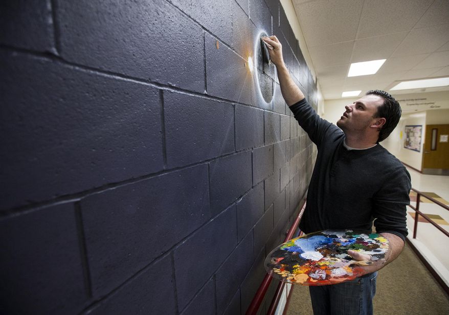 In this May 17, 2017 photo, local artist Jason Sanchez paints a galaxy mural in the front hallway of Ramsey Magnet School of Science in Coeur d'Alene, Idaho. Sanchez, a disabled Army veteran, has been spending several hours each weeknight since mid-April to complete the solar system mural at no cost to his childhood school. He plans to have it done in early June. (Loren Benoit/Coeur D'Alene Press via AP)