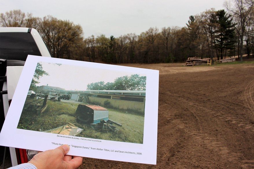 Developer Brian Bosgraaf holds up a photo of the former Broward Marine building that stood in this space in the 1990s during a May 4, 2017, tour of the Singapore Dunes north of Saugatuck. Bosgraaf is working with the property's new owner on plans for a 1,500-foot-long boat basin that would be built where the Broward building once stood. (Amy Biolchini /The Grand Rapids Press via AP)