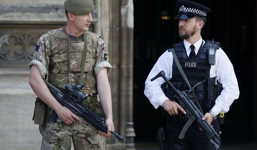 An armed soldier and policeman stand guard at Parliament, in London, Thursday, May 25, 2017. Armed troops are guarding vital locations in the country after the official threat level was raised to its highest point following a suicide bombing that killed more than 20 in Manchester. (AP Photo/Kirsty Wigglesworth)