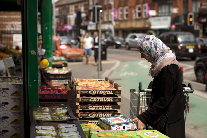 A woman buy vegetables in Curry Street in Manchester, Britain, Wednesday, May 24, 2017. On the Manchester street they call the "Curry Mile," there are very few Indian or Pakistani restaurants left. In a sign of the ever-changing face of this proudly multiethnic city, these days a hungry diner can choose between Halal snacks from Beirut, kebabs from Afghanistan or garishly colored sweets from India, among many others. (AP Photo/Emilio Morenatti)