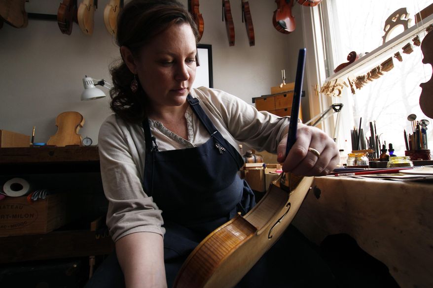 Sonja St. John applies varnish on a violin at her workshop in Neenah, Wis., on Thursday, April 27, 2017. Her brother, Jon St. John, died in Iraq in 2007 while serving in the military. Among other things, Sonja has found solace in her career, making and restoring violins. (AP Photo/Carrie Antlfinger)