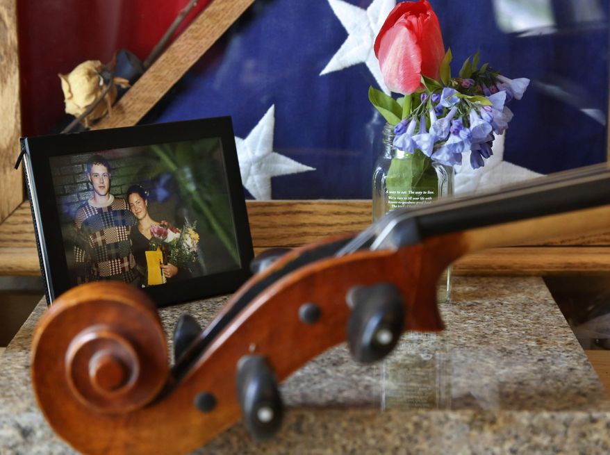 A photo of siblings Jon and Sonja St. John sits in Sonja's Neenah, Wis., home on Monday, May 8, 2017. Jon St. John, a specialist in the Army, died decade ago in Iraq when the military vehicle he was in hit a roadside bomb. He was 25. The photo is Sonja's favorite of the two of them. It was taken after he brought her flowers at one of her violin recitals. "He was a good friend to have," she says. The photo includes the flag that had been draped over Jon's casket during his military funeral. (AP Photo/Martha Irvine)