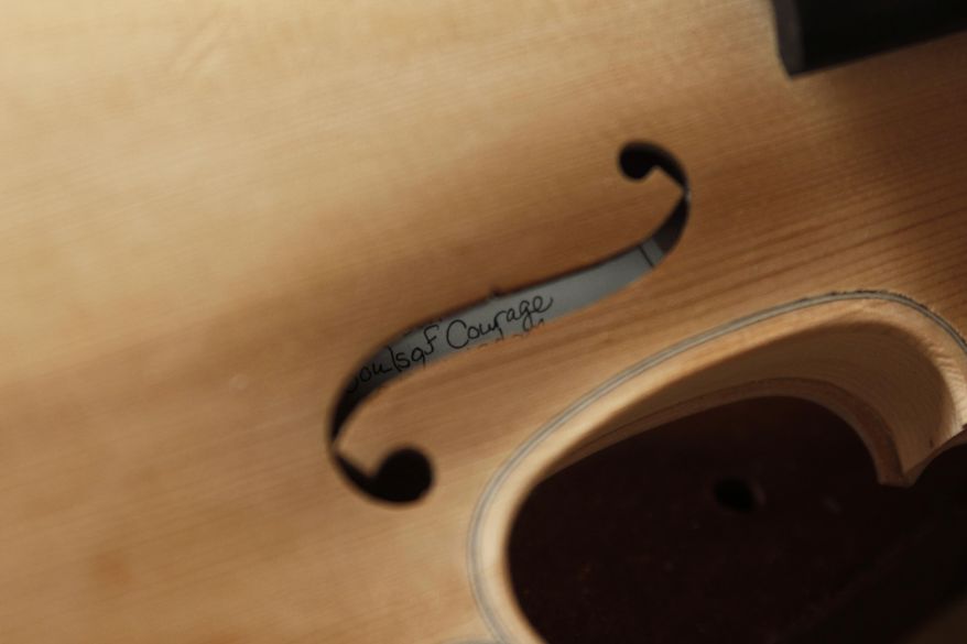 A message written by Sonja St. John is seen inside one of her handmade violins at her workshop in Neenah, Wis., on Thursday, April 27, 2017. The message reads, "In honor of past, present and future souls of courage and wisdom." St. John writes a different message for each violin she makes, always keeping her brother, Jon St. John, and other veterans in mind. (AP Photo/Carrie Antlfinger)