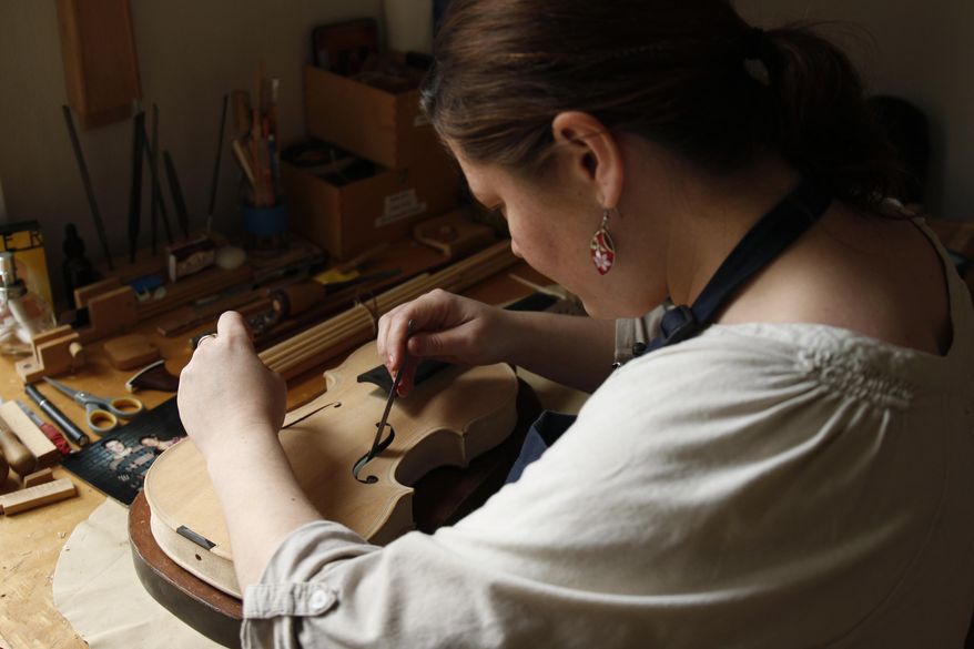 Sonja St. John inserts a note in one of her handmade violins at her workshop in Neenah, Wis., on Thursday, April 27, 2017. The message reads, "In honor of past, present and future souls of courage and wisdom." St. John writes a different message for each violin she makes, always keeping her brother, Jon St. John, and other veterans in mind. (AP Photo/Carrie Antlfinger)