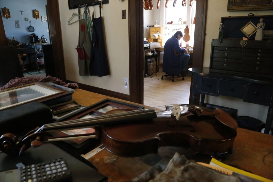 Sonja St. John sits in her workshop in her Neenah, Wis., home on Monday, May 8, 2017. Her brother, Jon St. John, died decade ago in the war in Iraq. Sonja has found solace in her career, making and restoring violins and also recently played violin on a song for her brother. It was written from her journal entries with the help of a nonprofit arts project for veterans called Warrior Songs. (AP Photo/Martha Irvine)