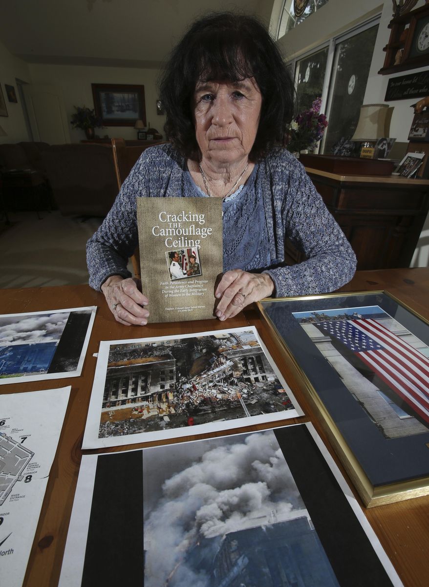In this Thursday, March 23, 2017 photo, U.S. Army Col. Janet Horton, a retired military chaplain of 28 years, poses for a photo with pictures of the Pentagon from the Sept. 11 terrorist attack and her book titled "Cracking The Camouflage Ceiling" at her home in southeast Ocala, Fla. The terrorist plane struck the south side of the building where her office was, but she had been called away to get dental X-rays. Ironically, she was supposed to get them on August 11, her birthday, but the dental assistant had misplaced her file. (Bruce Ackerman/Star-Banner via AP)