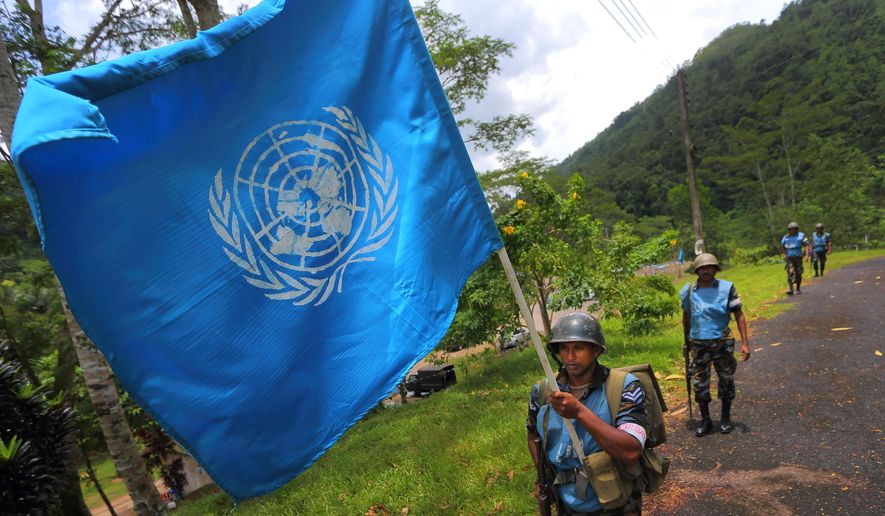 In this Sept. 13, 2016 photo, a Sri Lanka Air Force airman carries the U.N. flag during training for a road patrol at the Institute of Peace Support Operations Training in Kukuleganga, Sri Lanka. Instructors at the training camp said they have taken steps to address the risk of sexual abuse and exploitation since the child sex ring scandal in Haiti. (AP Photo/Eranga Jayawardena)