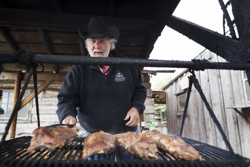 Mike Kesselring cooks ribs over a wood fire at the High Plains Homestead on May 1, 2017, in Crawford, Neb. The High Plains Homestead is a bed-and-breakfast, a guest ranch, a restaurant and much more. It's an oasis in the middle of the northwest corner of the state where people can disconnect and enjoy nature. (Ryan Soderlin/Omaha World-Herald via AP)