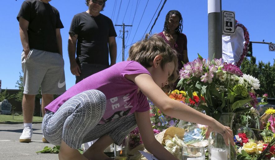 Coco Douglas, 8, leaves a handmade sign and rocks she painted at a memorial in Portland, Ore., on Saturday, May 27, 2017, for two bystanders who were stabbed to death Friday while trying to stop a man who was yelling anti-Muslim slurs and acting aggressively toward two young women. From left are Coco&#39;s brother, Desmond Douglas; her father, Christopher Douglas; and her stepmother, Angel Sauls. (AP Photos/Gillian Flaccus)