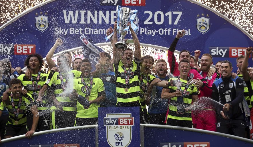Huddersfield Town&#39;s Mark Hudson lifts the trophy after winning the Sky Bet Championship play-off final at Wembley Stadium, London, Monday, May 29, 2017. Huddersfield Town will play in England&#39;s top division for the first time in 45 years after beating Reading 4-3 in a penalty shootout on Monday in the League Championship playoff final, world soccer&#39;s richest single game worth a minimum $220 million. (Nick Potts/PA via AP)