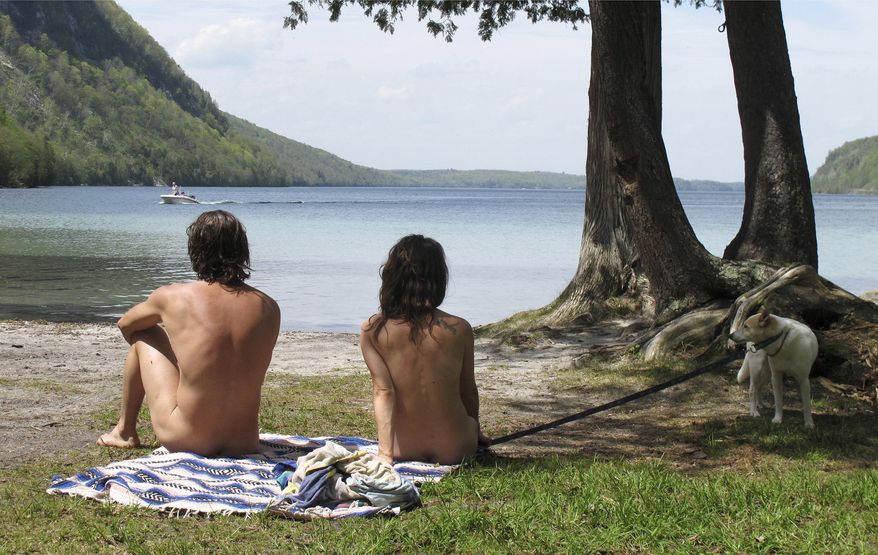 In this Thursday, May 18, 2017 photo, Michael Zarnowski, left, and Katelyn Comeau, of Thornton, N.H., relax at the clothing-optional beach known as the Southwest Cove of Lake Willoughby in Westmore, Vt. Located on state land, state officials said the area, which also includes hiking trails, gets so much use in the summer that upgrades need to be made to protect the area from over use. Beach users are opposed to the plan because they think it could threaten their ability to use the area. (AP Photo/Wilson Ring)