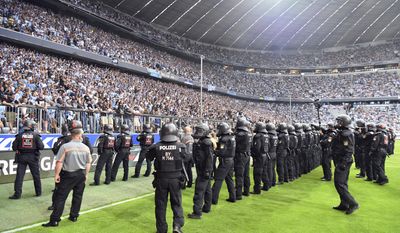Police officers and orderlies secure the pitch at the 80th minute after Munich fans started to riot during the first half of the German Bundesliga 2nd division relegation soccer match between TSV&#39;1860 Munich and Jahn Regensburg in the Allianz Arena in Munich, Germany, Tuesday, May 30, 2017. Former Bundesliga champion 1860 Munich was relegated from Germany’s second division in a game that was held up for 15 minutes toward the end because of violence from its angry fans. (Peter Kneffel/dpa via AP)