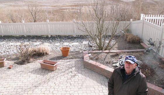 In this Feb. 16, 2017 photo Marty Mozzo poses in his backyard in Ocean City N.J. on the edge of a back bay wetlands. When he and his wife were considering buying the house, they looked at a small trickle of water in the distance and wondered if the property would flood, deciding the water was too far away to pose a danger. Within weeks, their house was surrounded by floodwaters. (AP Photo/Wayne Parry)
