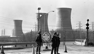FILE - In this undated file photo, a Pennsylvania state police officer and plant security guards stand outside the closed front gate to the Metropolitan Edison nuclear power plant on Three Mile Island near Harrisburg, Pa., after the plant was shut down following a partial meltdown on March 28, 1979. Exelon Corp., the owner of Three Mile Island, said Monday, May 29, 2017 it will shut down the plant in 2019 without a financial rescue from Pennsylvania.  (AP Photo/Paul Vathis, File)