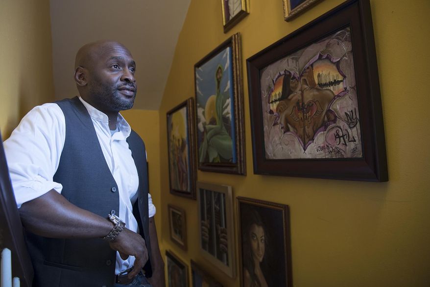 In this May 24, 2017, photo, artist Chris Fabor Muhammad poses for a photo with some of his work at his home in Paterson, N.J. Muhammad spent much of the past 15 years teaching in Paterson schools. He helped start a group that paints murals at various locations in the city and participates in anti-violence efforts. (Michael Karas/The Record via AP)