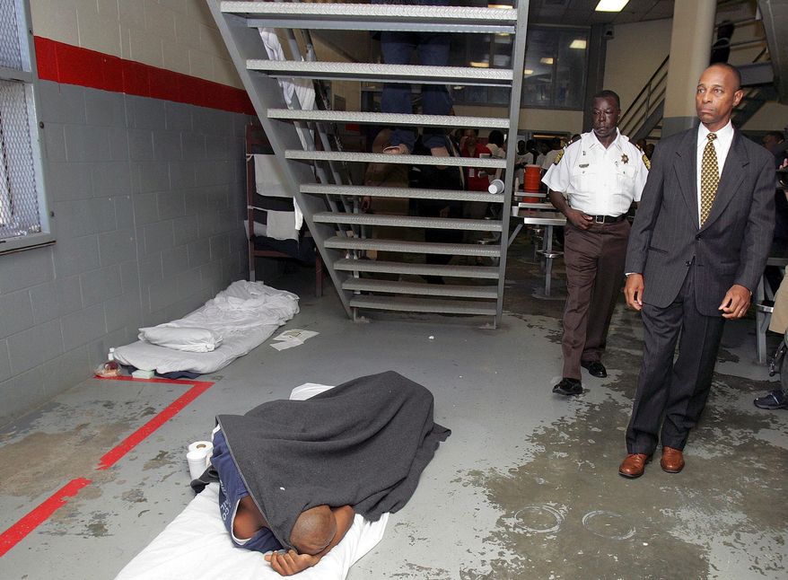 FILE - In this July 23, 2004 file photo John Gibson, right, and Capt. Jul Hull, left, walk past a prisoner sleeping on the floor of a cellblock at the Fulton County Jail in Atlanta. The Massachusetts-based Prison Policy Initiative, a criminal justice reform group, said in a study released Wednesday, May 31, 2017, Georgia and New Mexico, two states with some of the nation's largest percentages of minority residents, also had the country's highest jail incarceration rates in 2013. (AP Photo/Ric Feld, File)