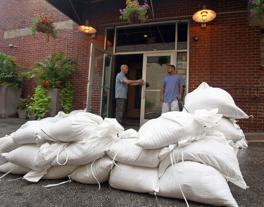 FILE -In this Saturday Aug. 27, 2011 file photo, People talk at a sandbagged entrance of the Manayunk Brewery and Restaurant, which is situated next to the Schuylkill river, as the establishment prepares for Hurricane Irene in Philadelphia. The National Hurricane Center will start issuing advisories giving deadlines for when communities should complete their storm preparations. The experimental advisories will show when tropical-storm force winds may hit particular communities to help them understand when it's too late to put up storm shutters or evacuate. (AP Photo/Jacqueline Larma, File)