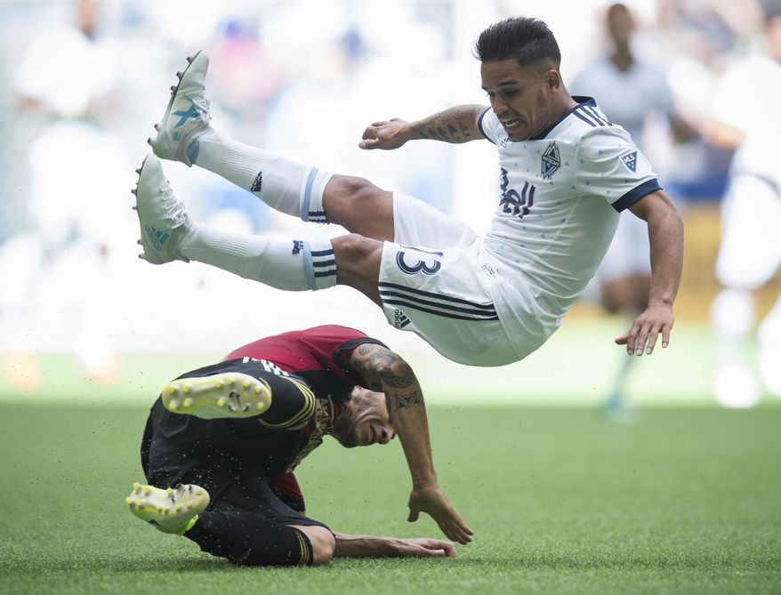 Vancouver Whitecaps' Cristian Techera, right, is upended by Atlanta United's Carlos Carmona during the second half of an MLS soccer match Saturday, June 3, 2017, in Vancouver, British Columbia. (Darryl Dyck/The Canadian Press via AP)