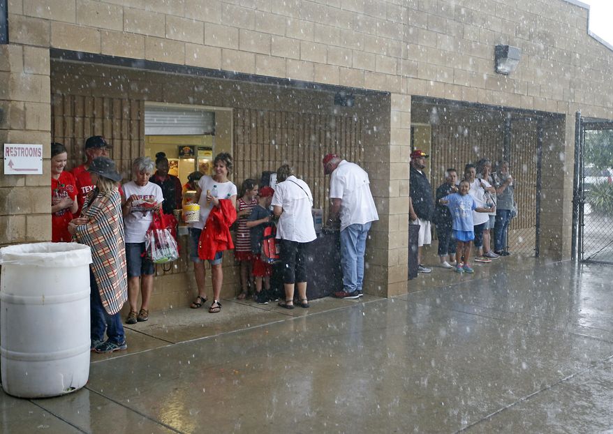 Fans stand by the concession stand to avoid the rain during an NCAA college baseball regional between Delaware and Texas Tech, Friday, June 2, 2017, in Lubbock, Texas. (Brad Tollefson/Lubbock Avalanche-Journal via AP)
