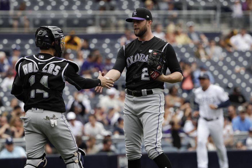 Colorado Rockies relief pitcher Jordan Lyles, right, celebrates with teammate catcher Tony Wolters (14) after defeating the San Diego Padres in a baseball game, Saturday, June 3, 2017, in San Diego. The Rockies won, 10-1. (AP Photo/Gregory Bull)
