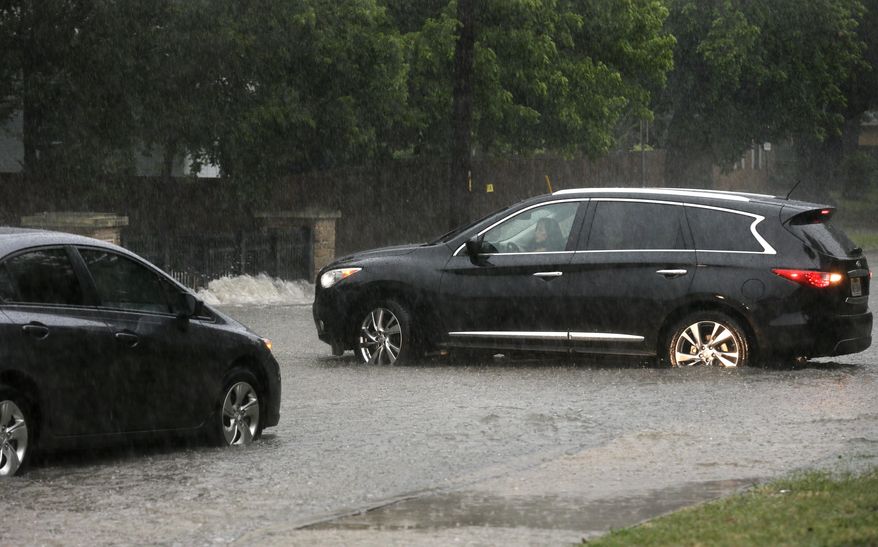 A driver on the left waits as another on the right, maneuvers her car to turn around rather than drive to a flooded neighborhood street caused by a swollen creek during a heavy rain shower, Friday, June 2, 2017, in Richardson, Texas. The (AP Photo/Tony Gutierrez)