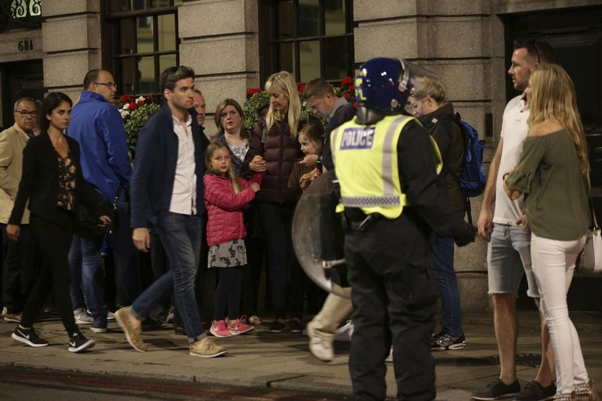 Guests from the Premier Inn Bankside Hotel are evacuated and kept in a group with police on Upper Thames Street following an attack in central London, Saturday, June 3, 2017. Terrorism struck at the heart of London, police said Sunday, after a vehicle veered off the road and mowed down pedestrians on London Bridge and gunshots rang out amid reports of knife attacks at nearby Borough Market. (Yui Mok/PA via AP)