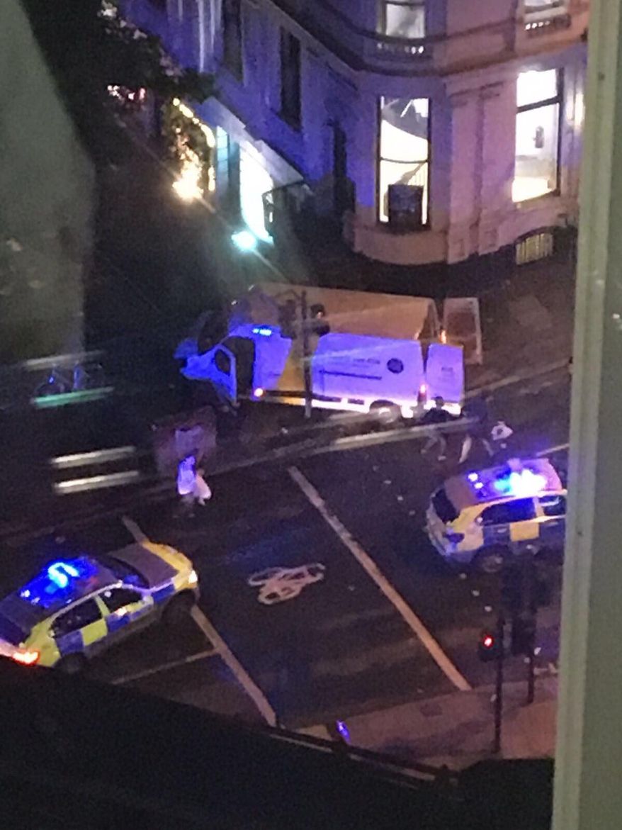 Police surround the van used by the attackers at London Bridge, Saturday June 3, 2017. The assault began Saturday night when a van veered off the road and barreled into pedestrians on busy London Bridge. Three men fled the van with large knives and attacked people at bars and restaurants in nearby Borough Market, police and witnesses said. (AP Photo/Kevin Dunne)