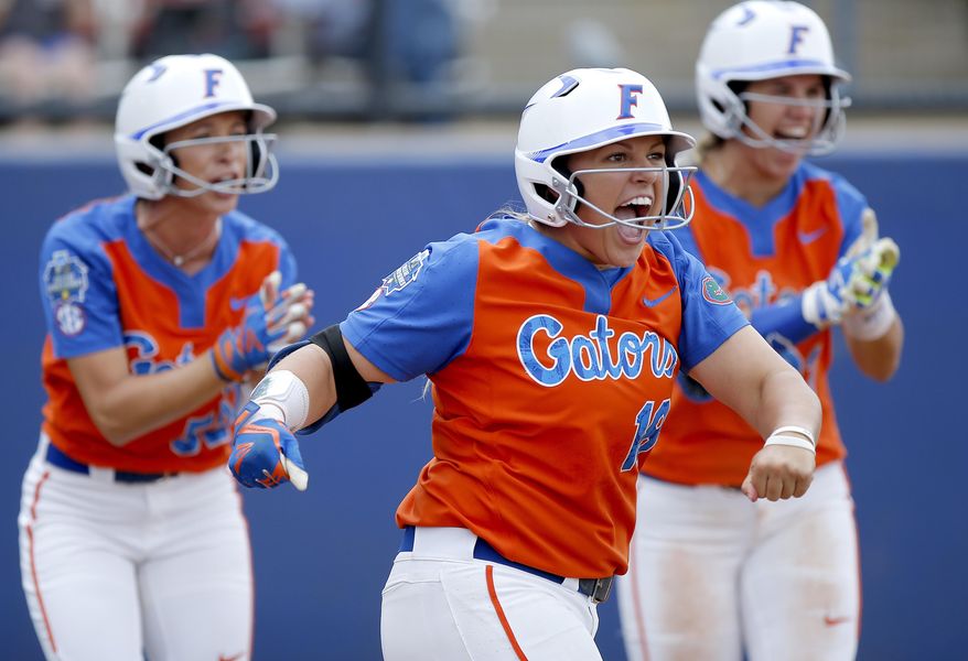 Florida's Amanda Lorenz (18), Justine McLean (52) and Nicole DeWitt (23) celebrate a score in the second inning during the Women's College World Series softball game against Washington in Oklahoma City, Sunday, June 4, 2017. (Sarah Phipps/The Oklahoman via AP)