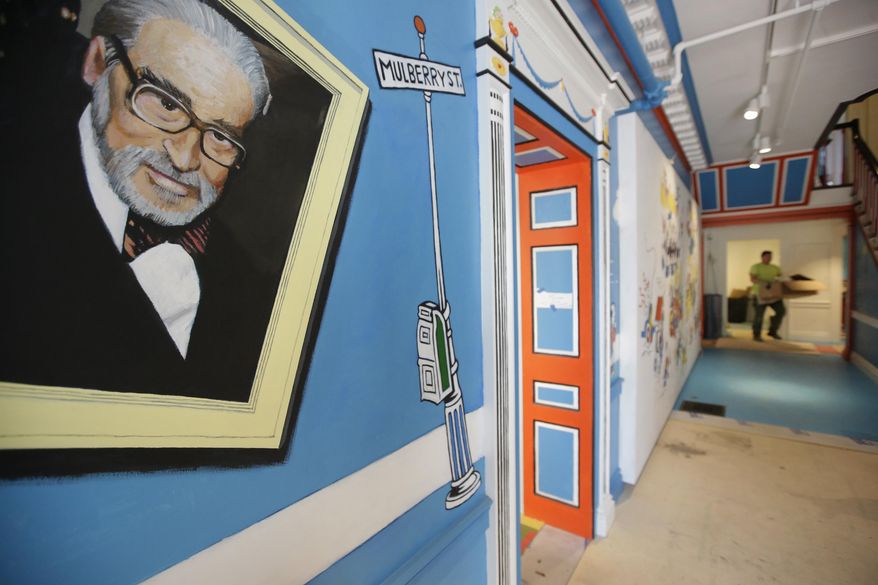 In this May 4, 2017, photo a mural that features Theodor Seuss Geisel, left, also know by his pen name Dr. Seuss, rests on a wall near an entrance at The Amazing World of Dr. Seuss Museum, in Springfield, Mass. The new museum devoted to Dr. Seuss opened on June 3 in his hometown. (AP Photo/Steven Senne)