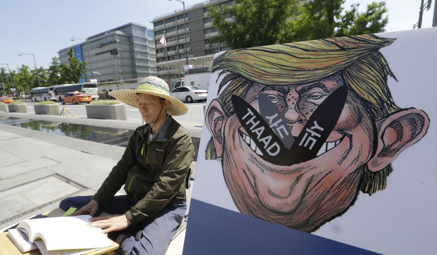 A South Korean protester sits next to a poster with an illustration of U.S. President Donald Trump to oppose a plan to deploy an advanced U.S. missile defense system called Terminal High-Altitude Area Defense, or THAAD, near the U.S. Embassy in Seoul Monday, June 5, 2017. South Korea&#39;s presidential office says a senior defense official has been suspended for deliberately failing to report the arrival of several more launchers for a contentious U.S. missile defense system meant to deal with North Korean threats. (AP Photo/Ahn Young-joon)