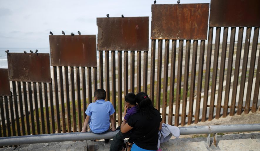 A family looks towards metal bars marking the U.S. border where it meets the Pacific Ocean in Tijuana, Mexico, on March 2, 2016. (Associated Press) **FILE**