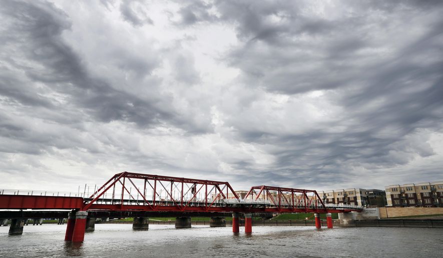 In this April 18, 2017, photo, the Red Bridge pedestrian bridge is seen over the Des Moines River in Des Moines, Iowa. A little more than a decade after it was restored, crews went back to the site with a crane to hoist the span more than 4 feet higher, at a cost of $3 million, after experts concluded that the river's flooding risk was double the previous estimates. (AP Photo/Charlie Neibergall)