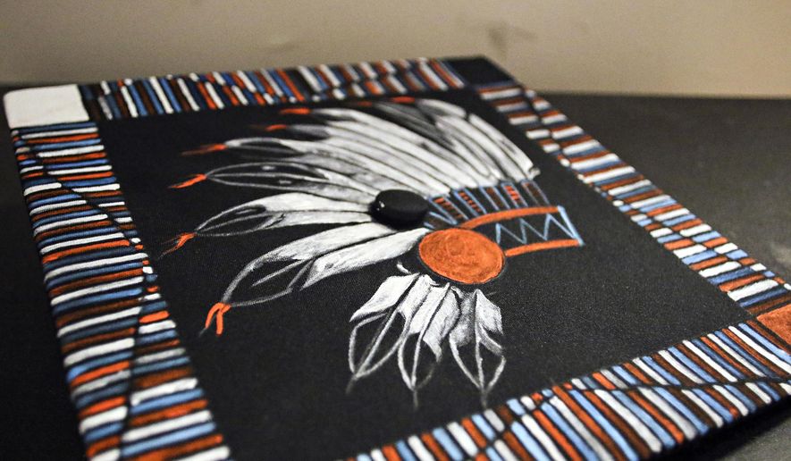 In this June 2, 2017, photo Zephrey Holloway's decorated mortarboard is displayed at Flathead High School's graduation in Kalispell, Mont. An administrator at the school prevented Holloway from wearing the mortarboard, painted by his grandmother, despite a new state law that allows Native American students to wear such regalia at special occasions. Principal Peter Fusaro issued an apology Monday, June 5, 2017, saying a school policy that disallowed graduates from using "tape, glitter, leis, bouquets or any other adornments" on caps and gowns was applied incorrectly. (Greg Lindstrom/Flathead Beacon via AP)