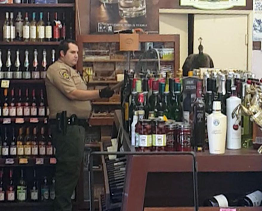 In this Monday, June 5, 2017 image made from cellphone video provided by Rani Ghanem, bottles tumble as an animal control officer attempts to net a female peacock that wound up inside the Royal Oaks Liquor Store in Arcadia, Calif. Store manager and college senior Rani Ghanem says he tried to guide the sharp-clawed bird outside but that she spooked, at one point flying directly toward him and then up onto a top shelf of the store. (Rani Ghanem via AP)
