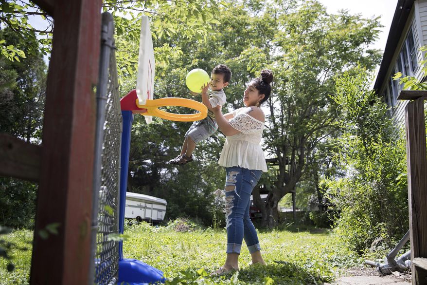 In this May 31, 2017 photo, Susie Gonzalez plays with her son Xavier outside their home in Omaha, Neb. Gonzalez dropped out of high school during her junior year when she gave birth to her son. Under a new state law, Nebraska public schools must outline how they'll address a number of challenges faced by teen parents. (Rebecca Gratz/Omaha World-Herald via AP)