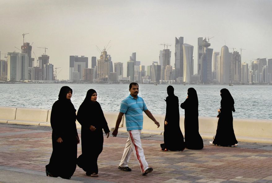 FILE- In this Saturday, April 7, 2012 file photo, the new high-rise buildings of downtown Doha, photographed in the background as Qatari women and a man walk by the sea in Doha, Qatar. Qatar, now facing a diplomatic crisis with other Arab nations, is a small country with a big history of turmoil and coups as it became one of the world's top suppliers of natural gas and now plans to host the 2022 FIFA World Cup. (AP Photo/Kamran Jebreili, File)