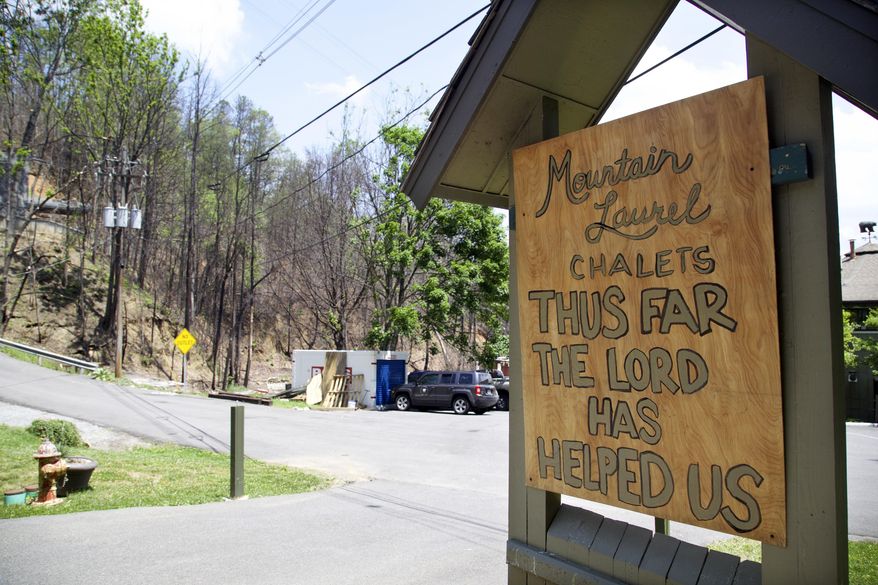 In this May 20, 2017 photo, a handmade sign stands in front of the fire-damaged Mountain Laurel Chalets. A deadly wildfire in November of 2016 put a dent in the tourism industry, but signs of growth are returning. (AP Photo/Kristin Hall)