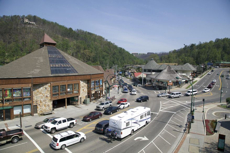 In this May 20, 2017 photo, a fire-damaged building overlooks cars driving through downtown Gatlinburg, Tennessee. A deadly wildfire in November of 2016 put a dent in the tourism industry, but signs of growth are returning. (AP Photo/Kristin Hall)