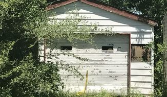 Trees grow in front of the entrance of a garage Tuesday, June 6, 2017, where the remains of a 7-year-old child was found in Centreville, Ill. A Las Vegas woman told investigators Tuesday that her dead child had been in a southern Illinois home for two years, and authorities later found human remains in the vacant house, according to authorities. Centreville police Sgt. DeMarius Thomas Sr. told the St. Louis Post-Disaptch that police believe the child was killed in nearby Belleville, Ill, and dumped in the garage. (Christine Byers/St. Louis Post-Dispatch via AP)
