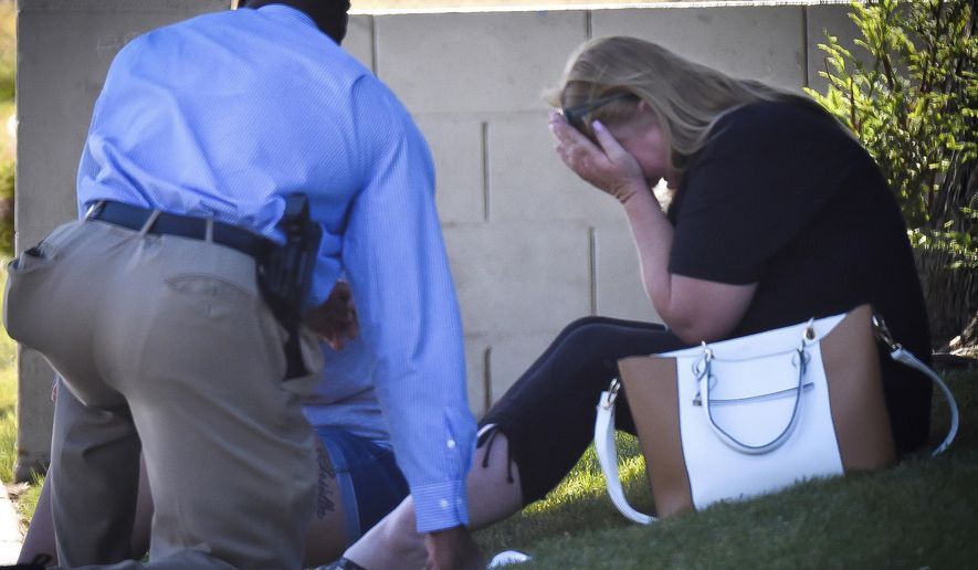 A Fresno police detective talks to family members of the man shot to death at a house where an officer involved shooting occurred Wednesday, June 7, 2017. Police say a suspected gang member was shot and killed early Wednesday after he fired a least 75 rounds at officers with a high-powered rifle. Officers were first called to the home following reports of gunfire from neighbors. (John Walker/Fresno Bee via AP)