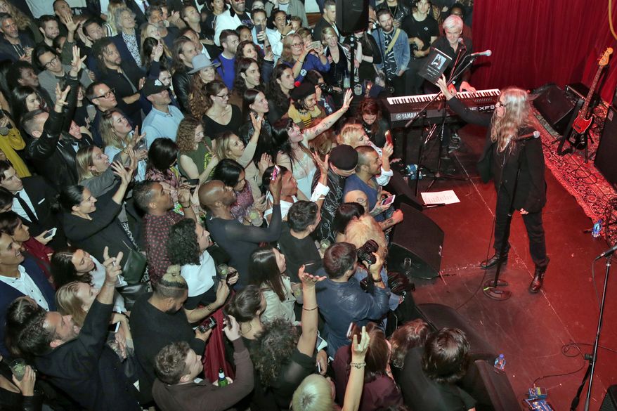 Singer Patti Smith tosses a copy of her book "Collected Lyrics 1970-2015" to the crowd after reading a passage before her performance in the Public Art space, during the PUBLIC Hotel opening party, in New York, Tuesday, June 6, 2017. The new hotel, opening Wednesday June 7, on Manhattan's Lower East Side, is the latest project from Ian Schrager, who's known for introducing the concept of boutique hotels and as co-founder of the legendary disco Studio 54. (AP Photo/Richard Drew)