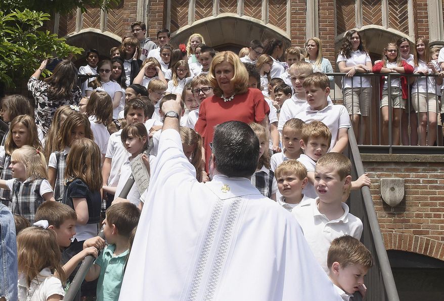 In this Friday, June 2, 2017 photo, Friar Larry Adams organizes the student body and staff for a group photo on the steps of St. Ursula Church on the last day of school for St. Ursula School, in Hampton Township, Pa. The school is closing and being consolidated. (Darrell Sapp/Pittsburgh Post-Gazette via AP)