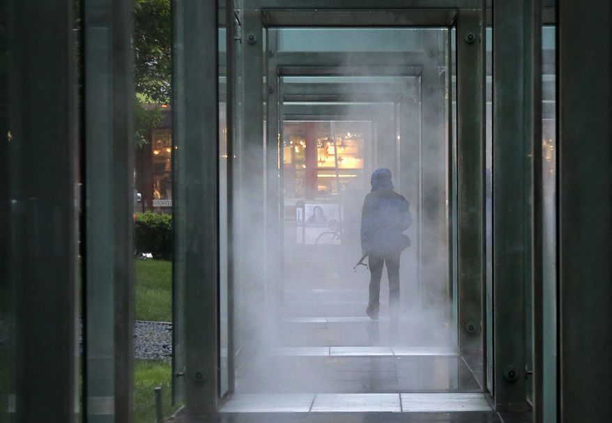In this Tuesday, June 6, 2017 photo, a visitor to the New England Holocaust Memorial walks under one of six metal and glass towers at the memorial in Boston. The film "Etched in Glass: The Legacy of Steve Ross," premiered Wednesday. The film recounts the holocaust survivor's five years spent in Nazi concentration camps as a child. Steve Ross is the founder of the New England Holocaust Memorial. (AP Photo/Steven Senne)