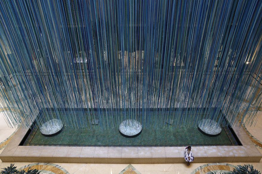 A girl sits near an art installation titled "Another Sky" by artist Anne Patterson, Thursday, June 8, 2017, in Las Vegas. The installation, at the Palazzo hotel and casino, consists of around 3,500 ribbons suspended from the ceiling. (AP Photo/John Locher)